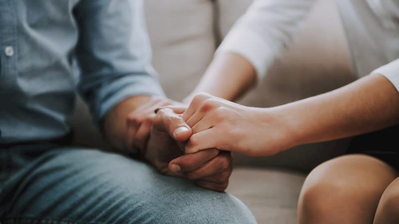 A woman squeezing the hand and arm of a man to stimulate the parasympathetic nervous system.