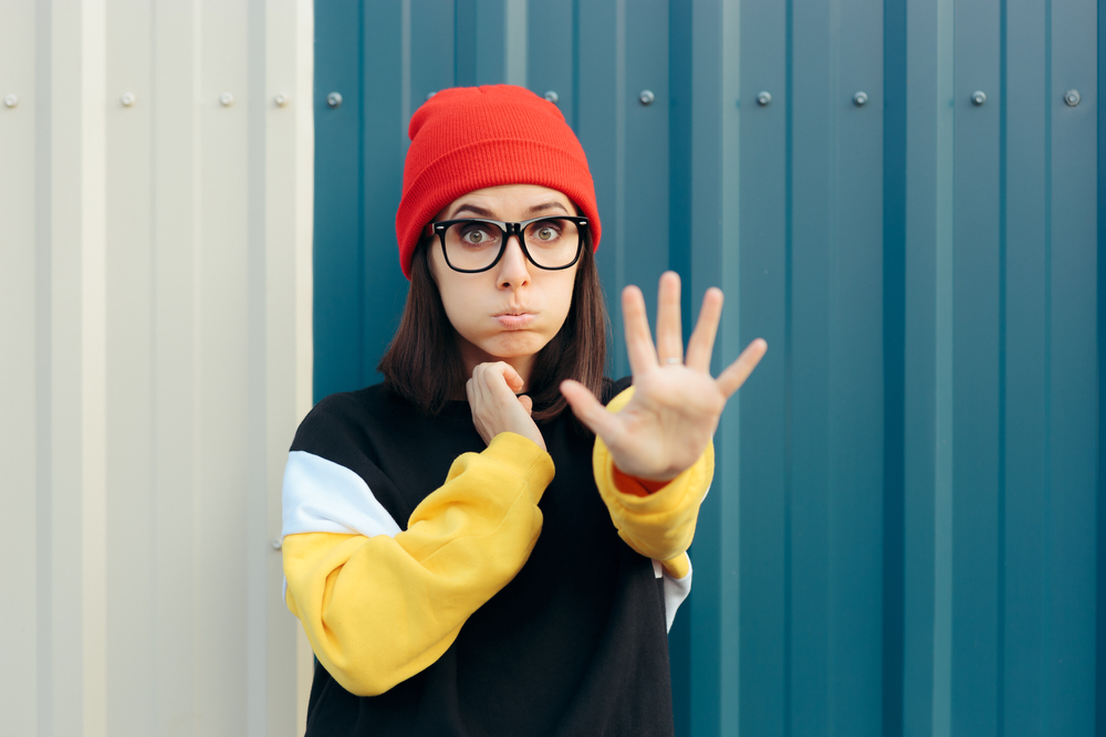 A stern young woman holds her hand out to stop someone and stays firm in her boundaries